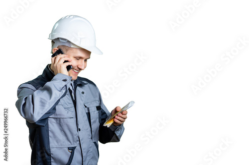 A builder in a white helmet on a white background talking on the phone and looks at the money in his hands. Great day for salary. Isolated