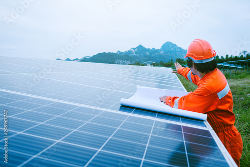 engineer in solar power plant working on installing solar panel ; smart operator holding blueprint for installing equipment in solar power plant