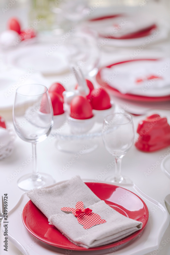 Happy easter. Decor and table setting of the Easter table is a vase with white tulips and dishes of red and white color. Easter colored eggs with white polka dots. Happy easter. Decor and table setting of the Easter table is a vase with white tulips and dishes of red and white color. Easter colored eggs with white polka dots.