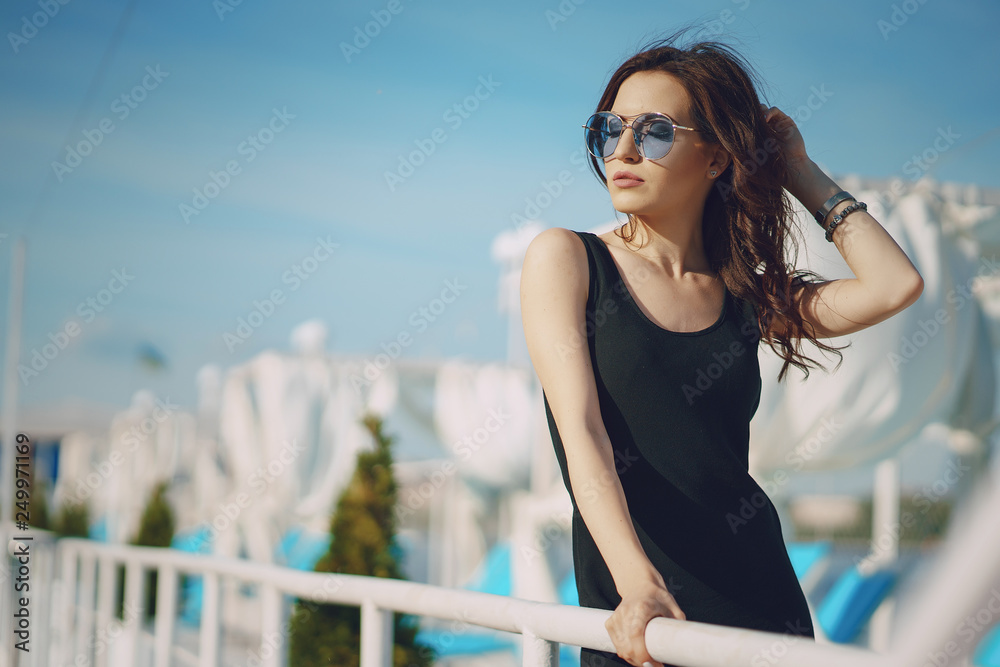 A beautiful young girl with curly hair and glasses standing by the water