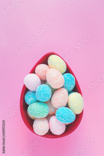 Happy Easter greeting card with small eggs in an egg shaped bowl, on pink background with copy space in flat lay © taniasv