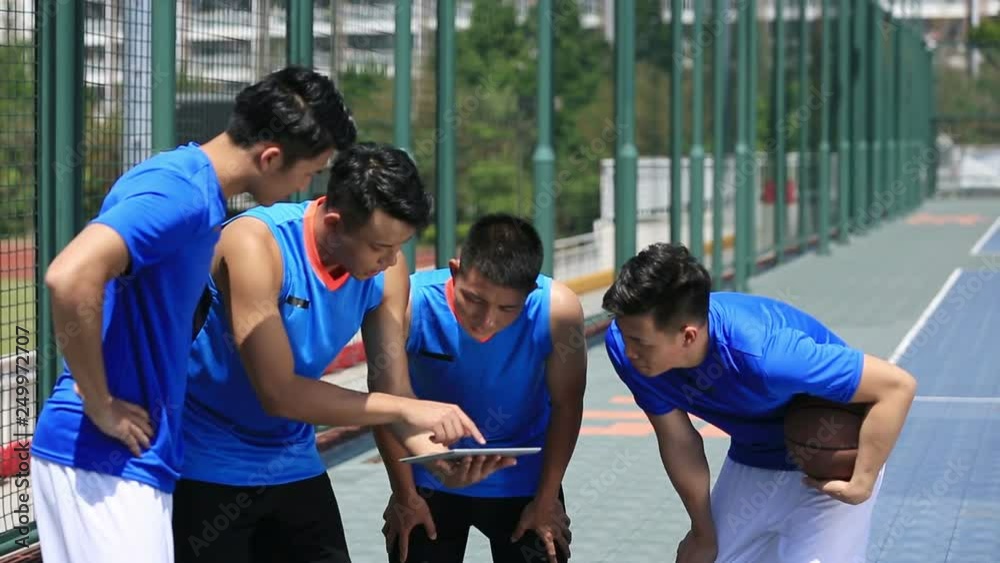 group of asian young adult basketball players discussing tactics using digital tablet. group of asian young adult basketball players discussing tactics using digital tablet.