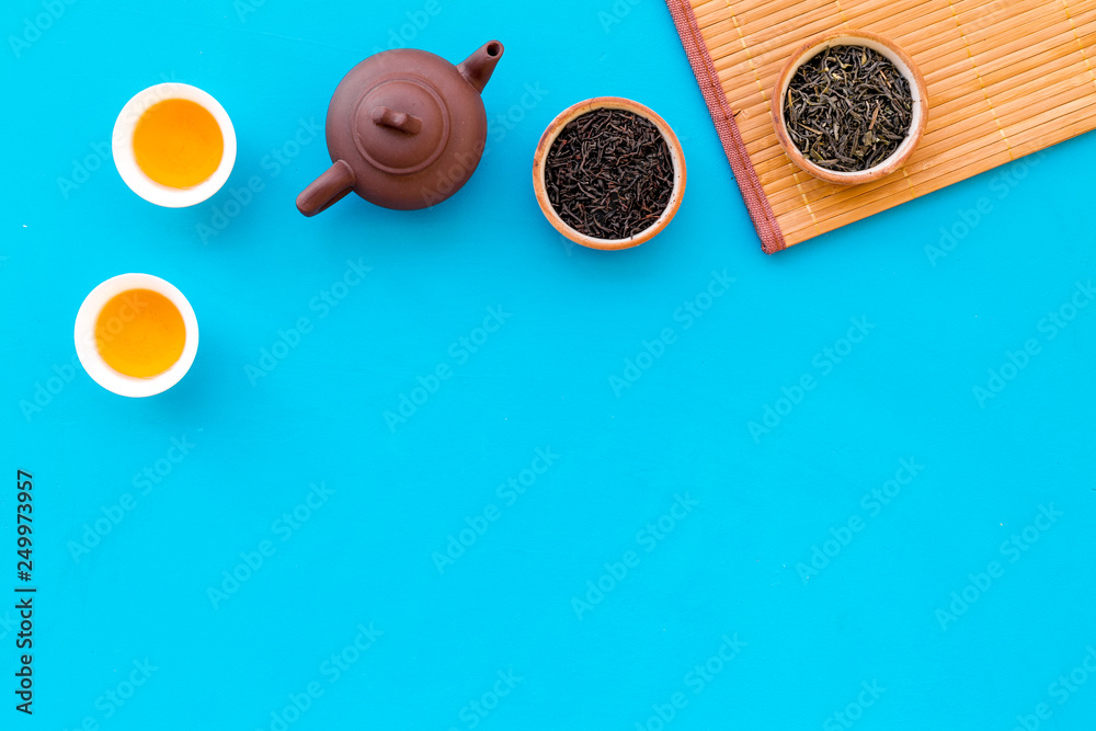 Chinese tea ceremony concept. Tea pot, tea cup, dry tea leaves, bamboo mat on blue background top view copy space pattern Chinese tea ceremony concept. Tea pot, tea cup, dry tea leaves, bamboo mat on blue background top view copy space pattern