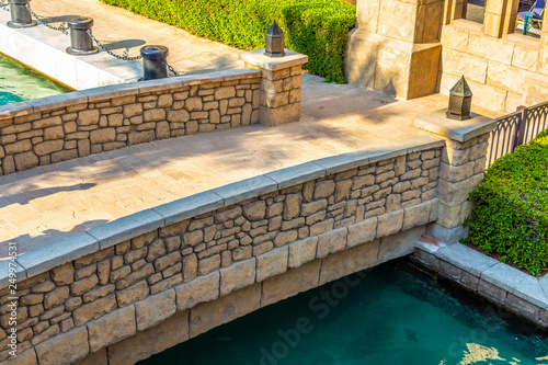 Decorative stone bridge through an artificial channel with azure water.