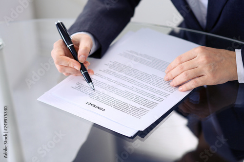 Unknown female hands with pen over document of contract. Agreement signing or business concept