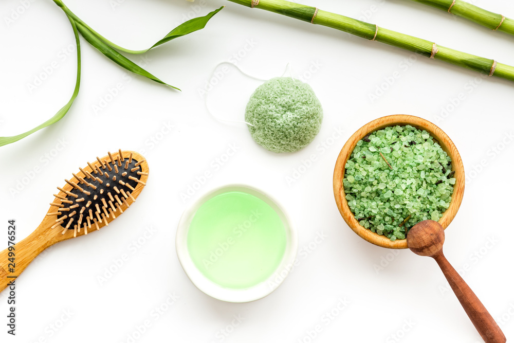 Asian spa treatment concept with natural ingredients. Spa salt, lotion, sponge near bamboo on white background top view pattern Asian spa treatment concept with natural ingredients. Spa salt, lotion, sponge near bamboo on white background top view pattern