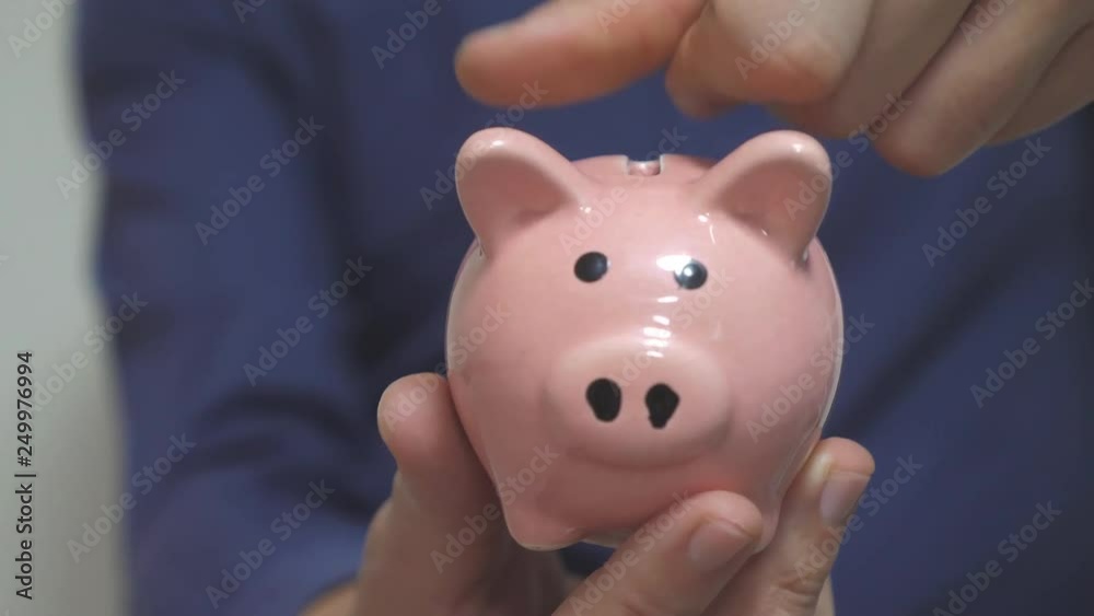 businessman man makes savings puts coins in a piggy bank. piggy bank business concept. slow motion video. saving money is an investment for the future. Banking investment and finance. hand is putting businessman man makes savings puts coins in a piggy bank. piggy bank business concept. slow motion video. saving money is an investment for the future. Banking investment and finance. hand is putting