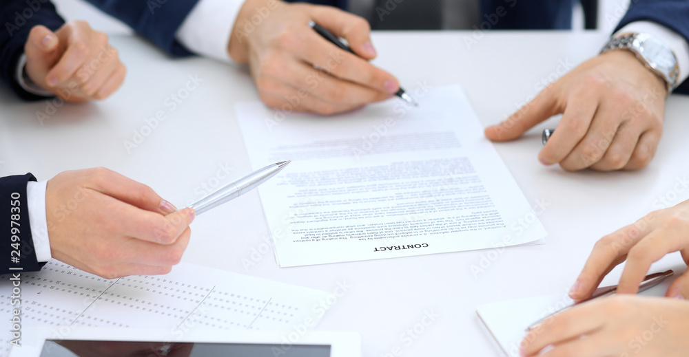 Group of business people and lawyers discussing contract papers sitting at the table, close-up. Successful teamwork, cooperation and agreement concepts Group of business people and lawyers discussing contract papers sitting at the table, close-up. Successful teamwork, cooperation and agreement concepts