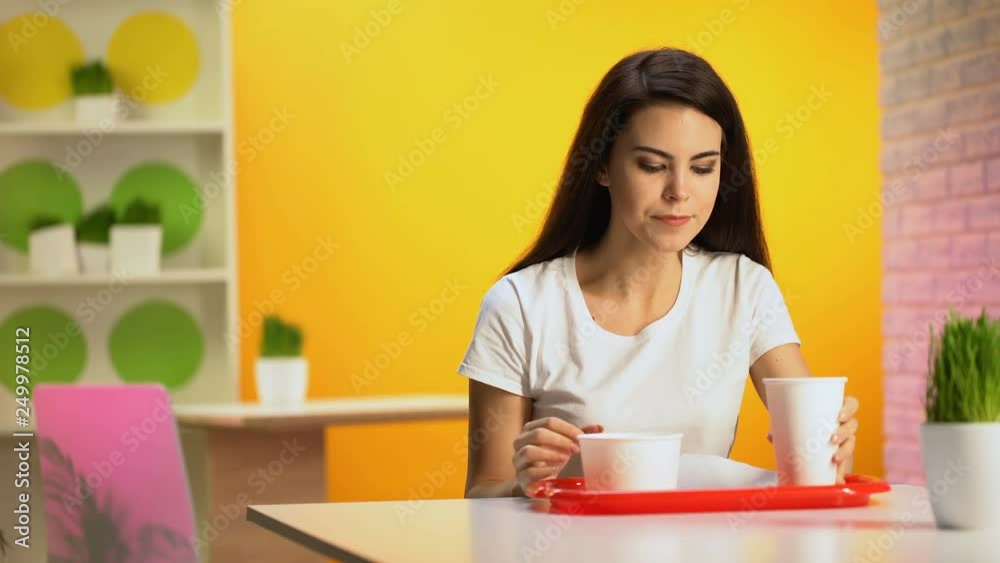 Young woman drinking from disposable glass and wiping mouth after meal, cafe Young woman drinking from disposable glass and wiping mouth after meal, cafe