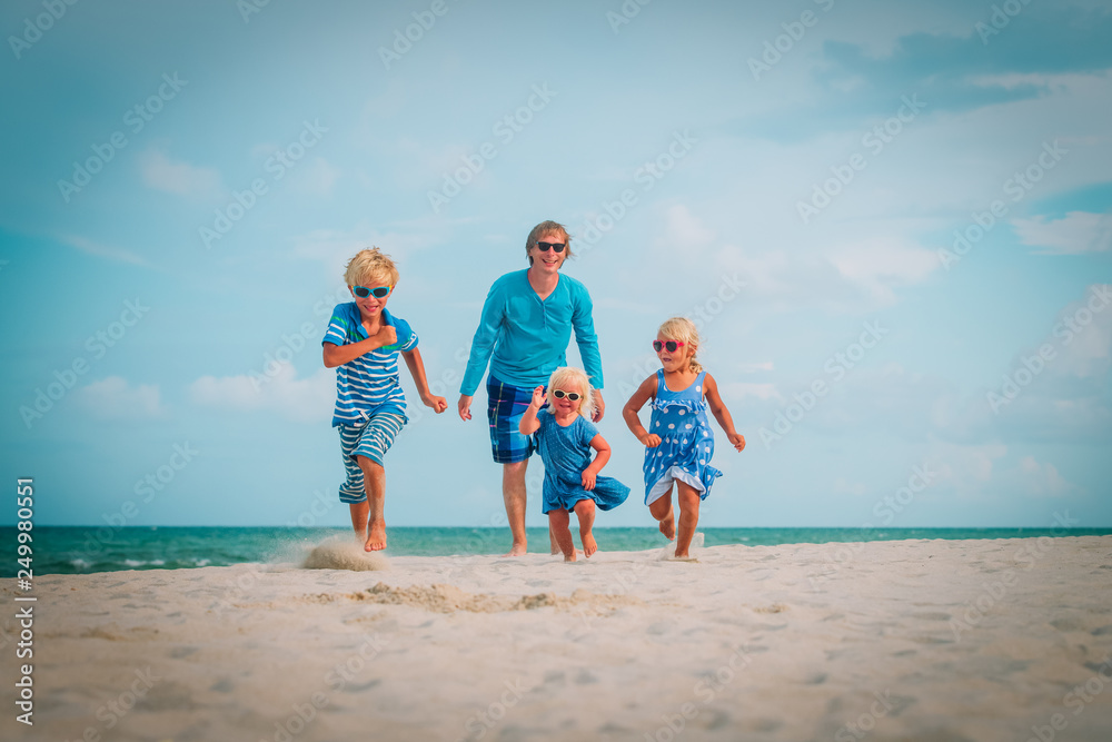 father with kids -son and daughters- run at beach