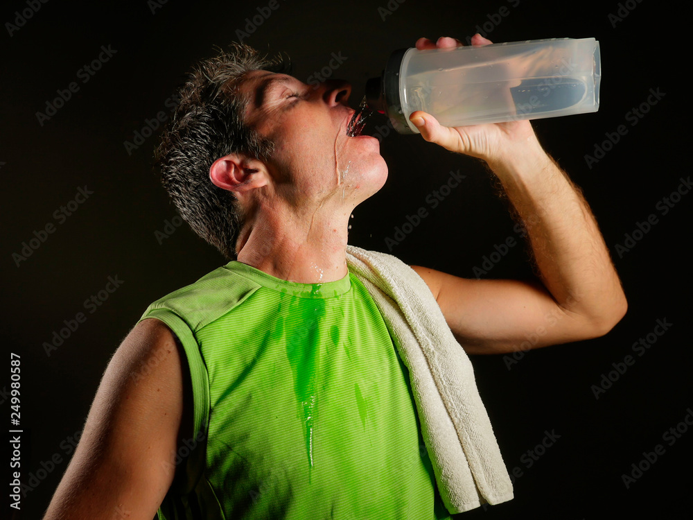 young sweaty attractive and fit sport man drinking water holding bottle cooling off after hard fitness workout at gym club isolated on black background in healthy lifestyle young sweaty attractive and fit sport man drinking water holding bottle cooling off after hard fitness workout at gym club isolated on black background in healthy lifestyle