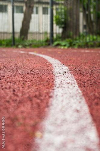 Running lane with red rubber surface and white line in the middle, low angle view