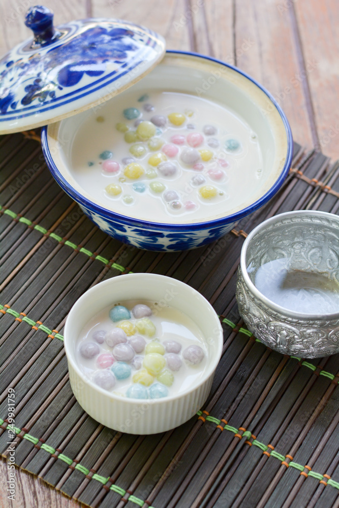 Color of Rice Dumpling in Coconut Milk (Bua Loy) in white bowl on wooden table for served in party. Famous dessert in Thailand. Sweet and delicious food. Color of Rice Dumpling in Coconut Milk (Bua Loy) in white bowl on wooden table for served in party. Famous dessert in Thailand. Sweet and delicious food.