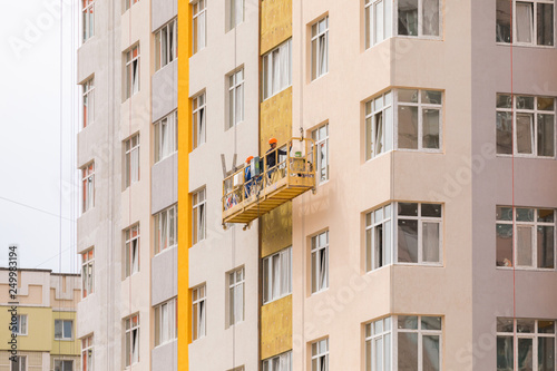 Builders paint the facade of a high-rise residential building © LALSSTOCK