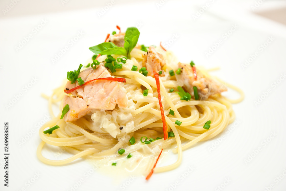 Spaghetti with salmon, cream cheese and spinach close-up on white plate Spaghetti with salmon, cream cheese and spinach close-up on white plate