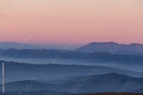 Beautifully colored sky at dusk, with mountains layers and mist between them