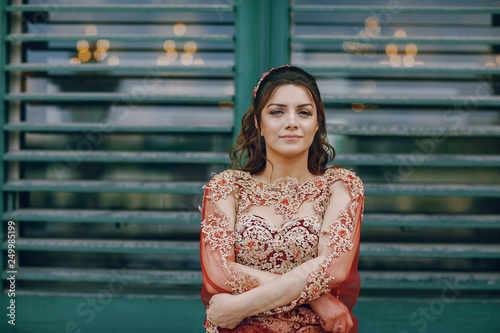 A beautiful Turkish girl in a long red dress walks in the summer old city