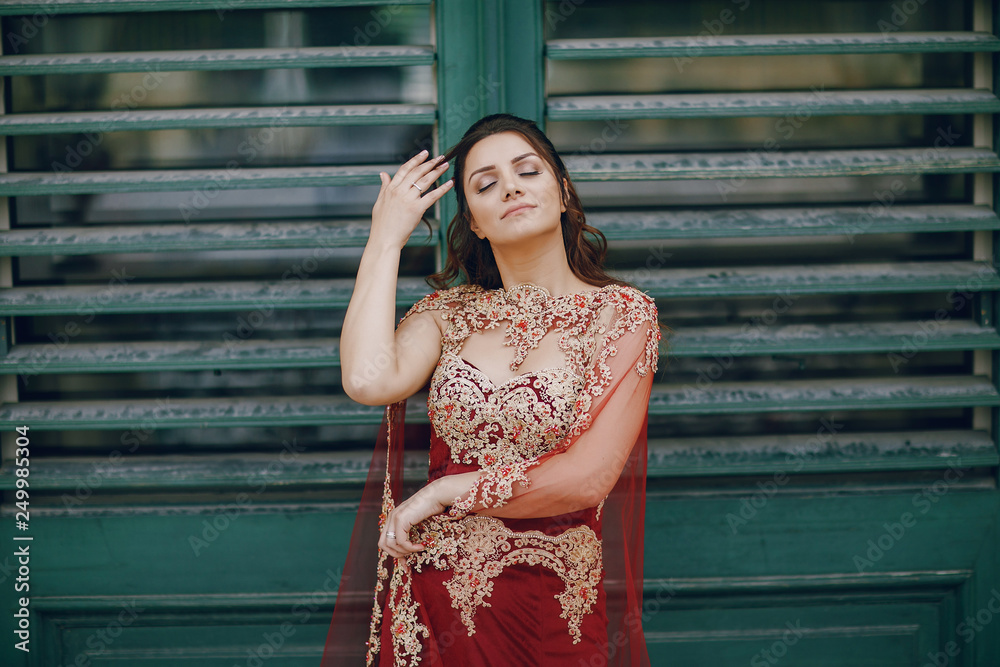 A beautiful Turkish girl in a long red dress walks in the summer old city A beautiful Turkish girl in a long red dress walks in the summer old city