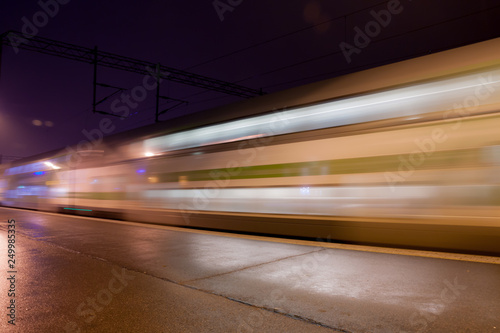 Train in motion on the station at night, long exposure photo.