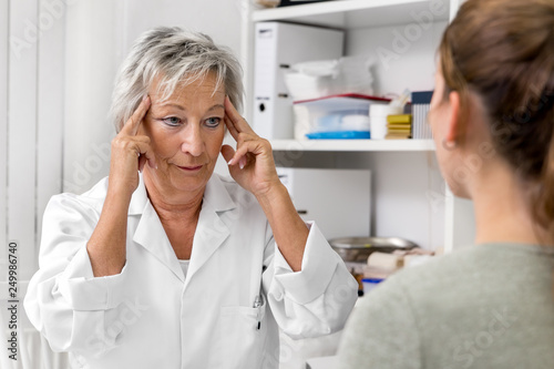 Ärztin deutet auf ihre Schläfen, Konzept Kopfschmerzen und Schläfenschmerzen