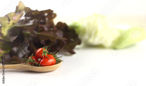 Fresh tomato on wooden spoon against blur vegetables background