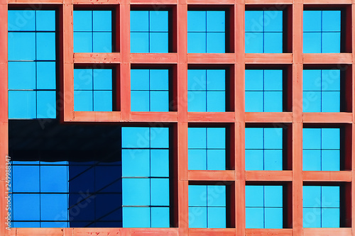 Geometric architectural background of blue and coral color. Skyscraper glass windows.