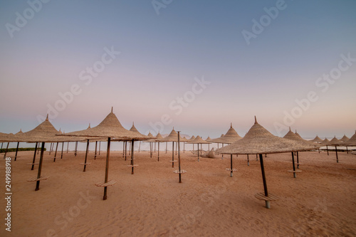 straw umbrellas on sandy sea  ocean  beach on exotic resort. summer landscape