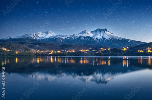 natural background with snow-covered volcano, starry sky with Milky way and reflection in a mountain lake photo