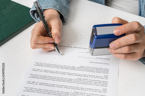 Fotografie Business woman putting stamp on documents in the office