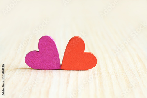 Magenta and orange wooden hearts on wooden board