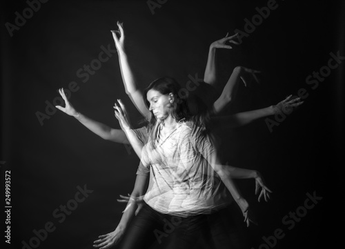 Stroboscopic photo of young woman with moving arms on dark background photo