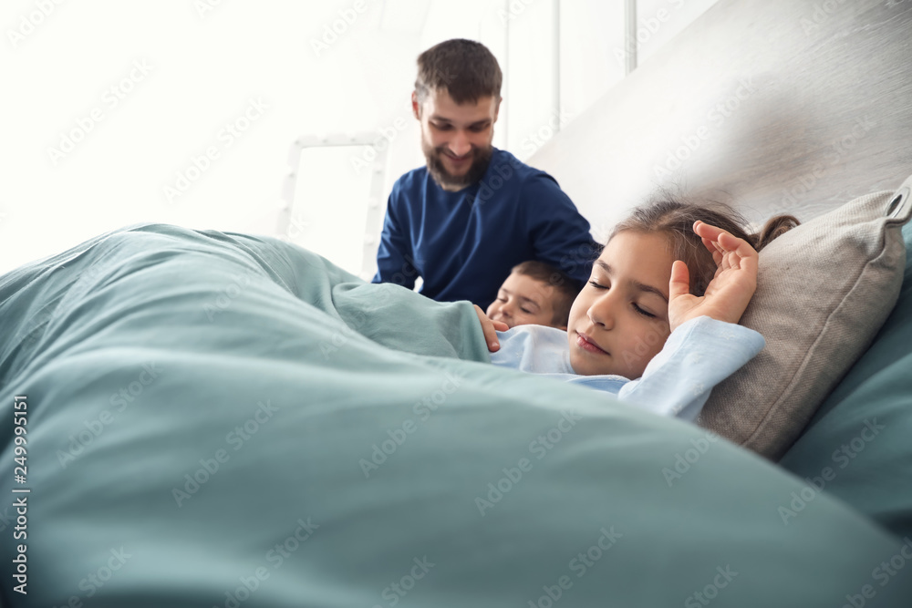 Young father getting children to sleep at home Young father getting children to sleep at home