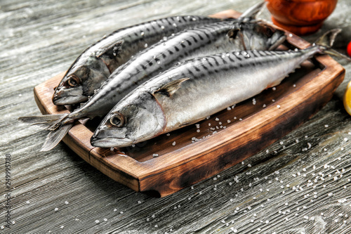 Board with tasty raw mackerel fish on wooden table photo