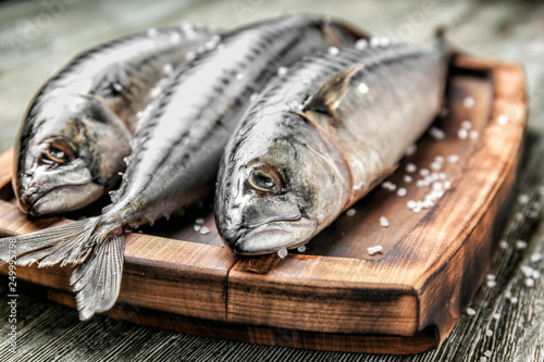 Wooden board with tasty raw mackerel fish on table photo