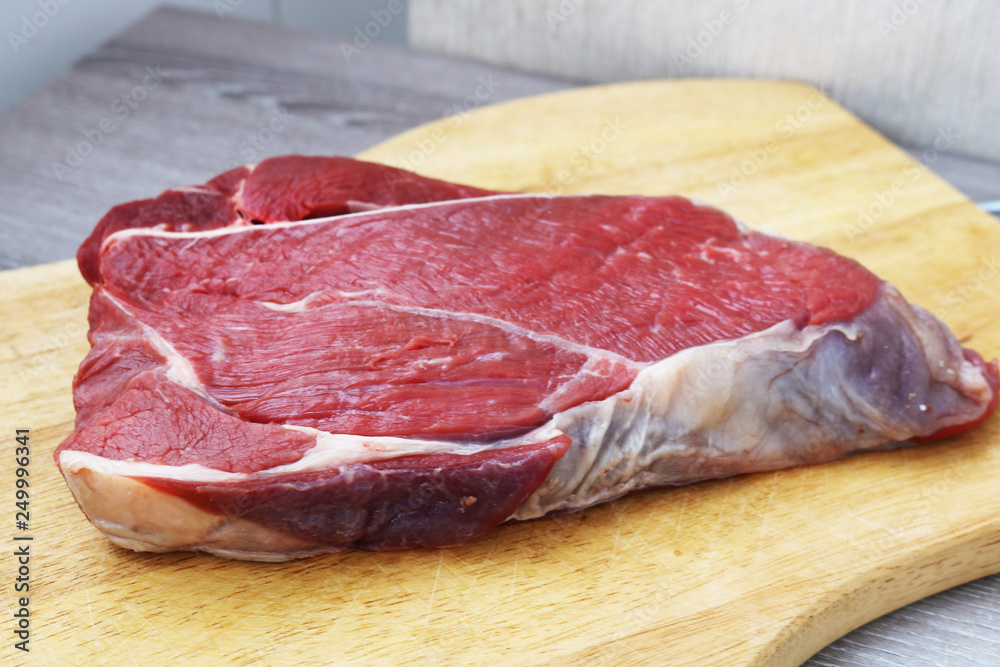 Fresh raw beef steak on wooden background, top view Fresh raw beef steak on wooden background, top view