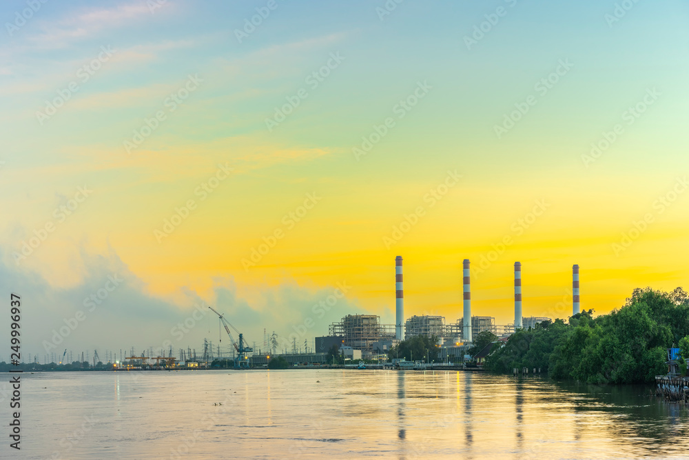 Natural gas electric power plant with smokestack at riverside in chonburi thailand and beautiful golden sunrise sky in morning