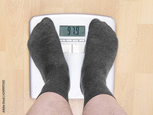 overweight man in socks standing on bathroom scales