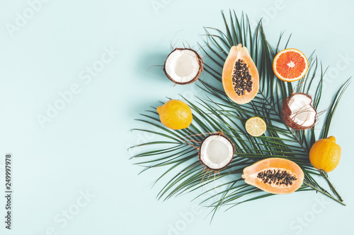 Fruits and palm leaves on pastel blue background. Tropical fruits. Summer concept. Flat lay, top view, copy space