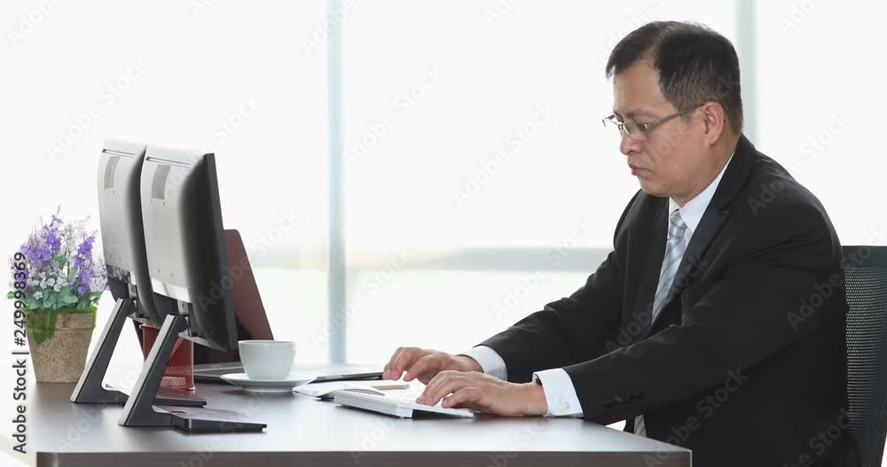 Close up scene video of senior Asian businessman using computer alone there are two monitors in modern office. Close up scene video of senior Asian businessman using computer alone there are two monitors in modern office.