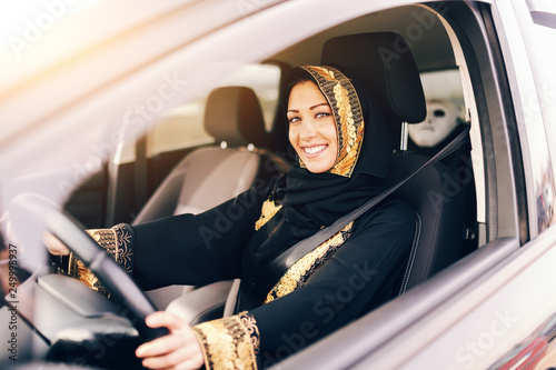 Εκτύπωση καμβά Beautiful muslim woman with toothy smile driving car.