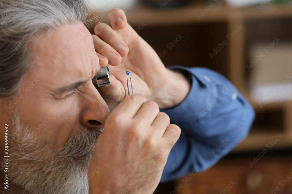 Fototapeta premium Jeweller examining gemstone in workshop