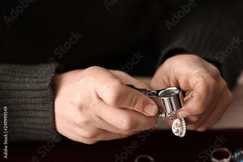 Jeweller examining gemstone in earring, closeup