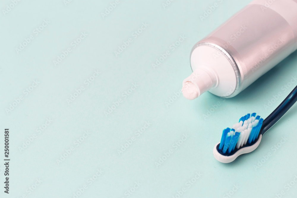 Toothpaste in tube and toothbrush on blue background. Dental hygiene concept.