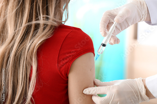 Doctor vaccinating woman against flu in clinic