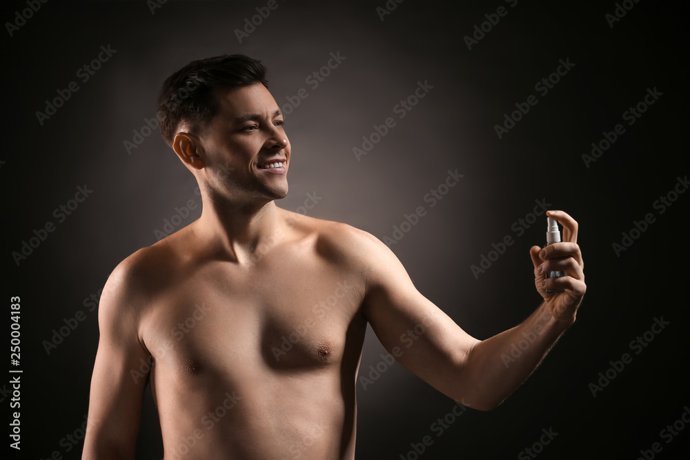 Handsome man with bottle of perfume on dark background Handsome man with bottle of perfume on dark background