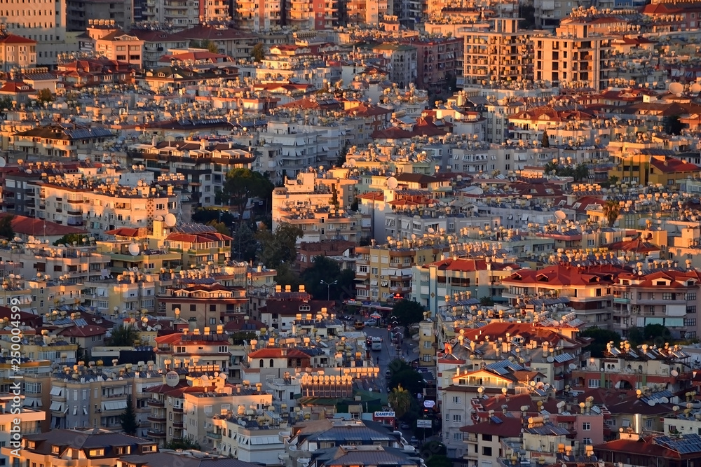 Residential areas of the Turkish city of Alanya with a bird's eye view at sunset. Dense low building and the street passing in the middle. Roofs of houses