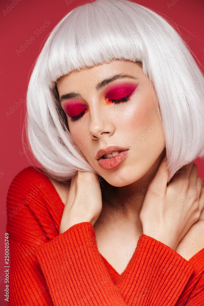 Woman isolated over red wall background with bright makeup posing with eyes closed. Woman isolated over red wall background with bright makeup posing with eyes closed.
