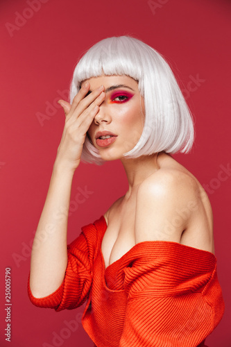 Beautiful young woman isolated over red wall background with bright makeup posing.