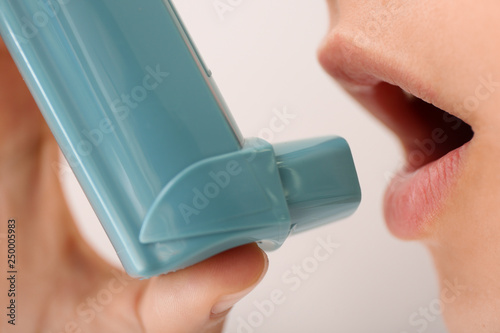 Young woman using inhaler a...