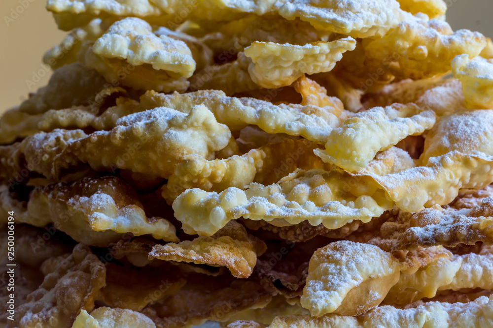 Close-up.Sweet dessert Angel wings.Deep-fried dough strips sprinkled with powdered sugar. Background for a site about regional cuisine, baking,sweets. Close-up.Sweet dessert Angel wings.Deep-fried dough strips sprinkled with powdered sugar. Background for a site about regional cuisine, baking,sweets.